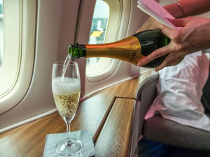 a person pouring champagne into a glass on an airplane