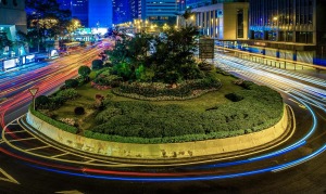 a circular flower bed with plants and lights on the side of the road