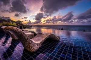 a pool with a view of the ocean and a cloudy sky