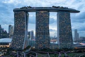 a tall buildings with lights on with Marina Bay Sands in the background
