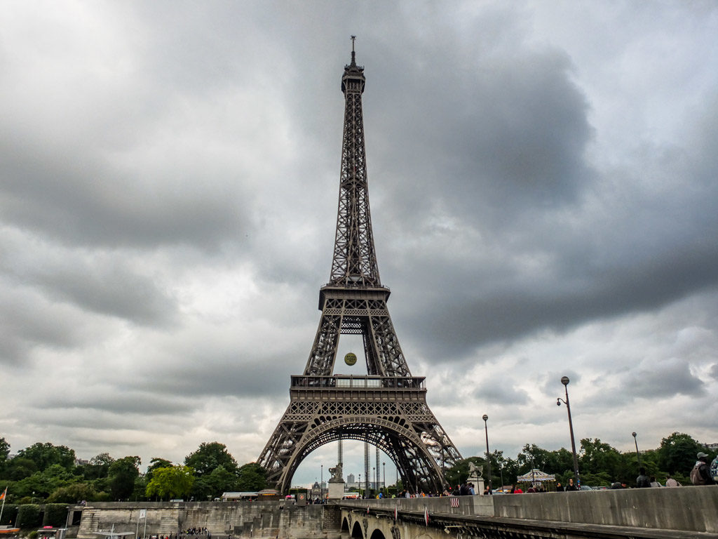 a large metal tower with Eiffel Tower and trees