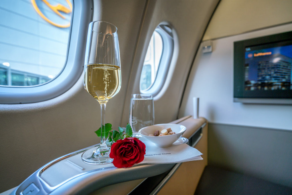a glass of champagne on a tray with a rose on the side of the plane
