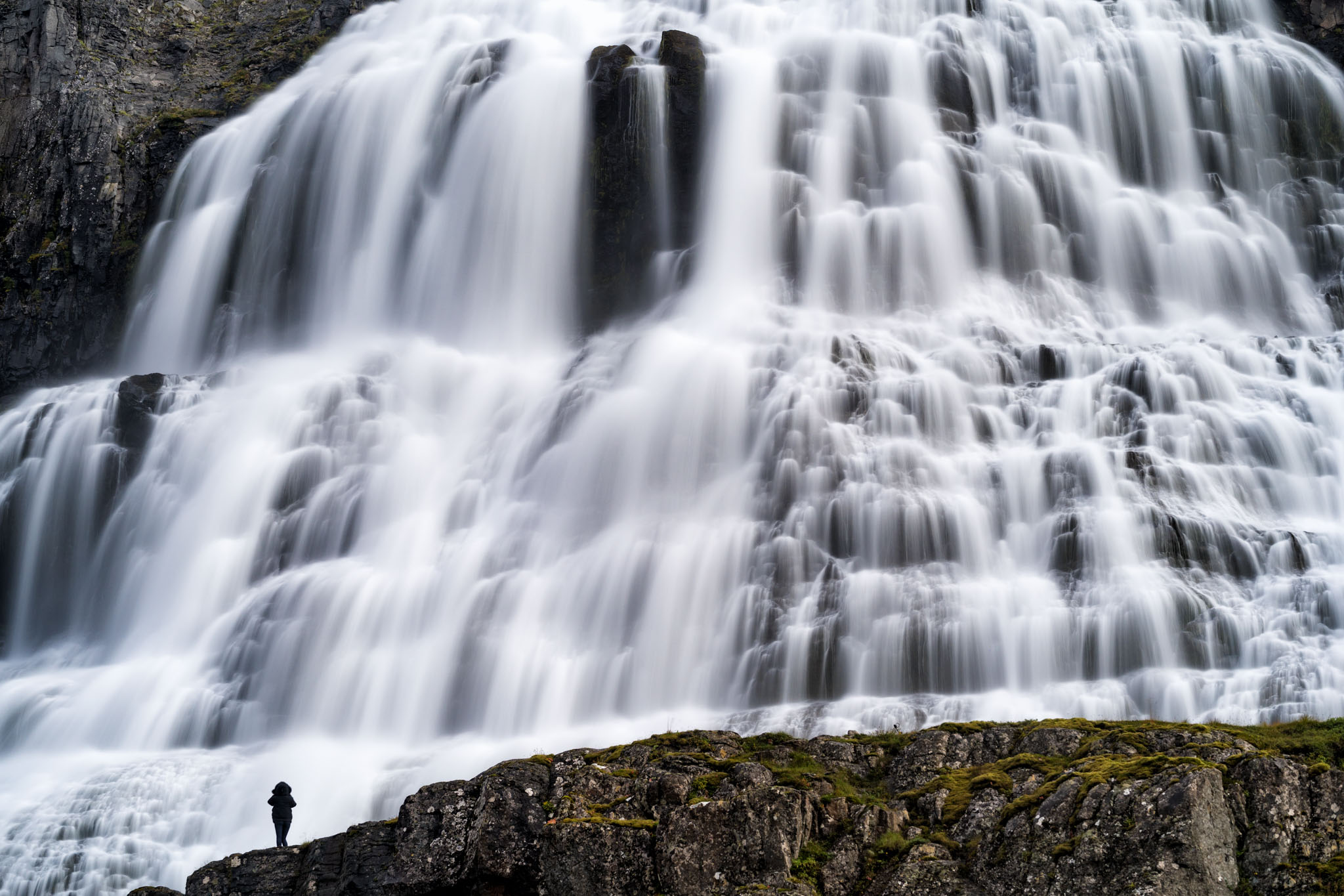 a person standing on a rock with a waterfall