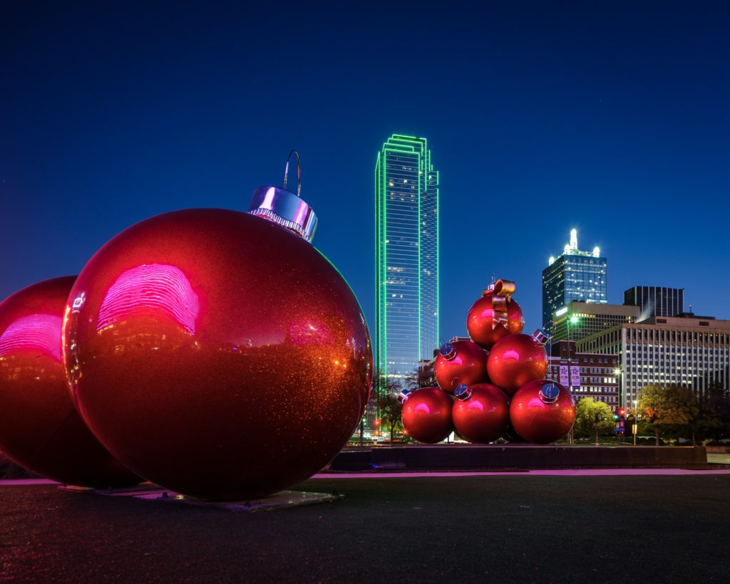 large red ornaments in front of a city skyline