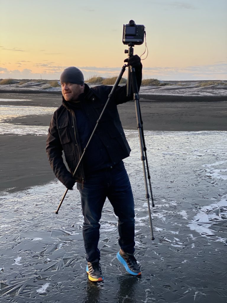 a man holding a camera and standing on ice