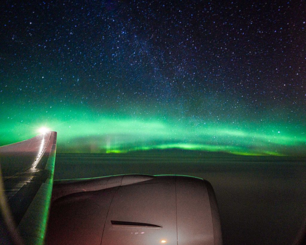 an airplane wing with green lights in the sky