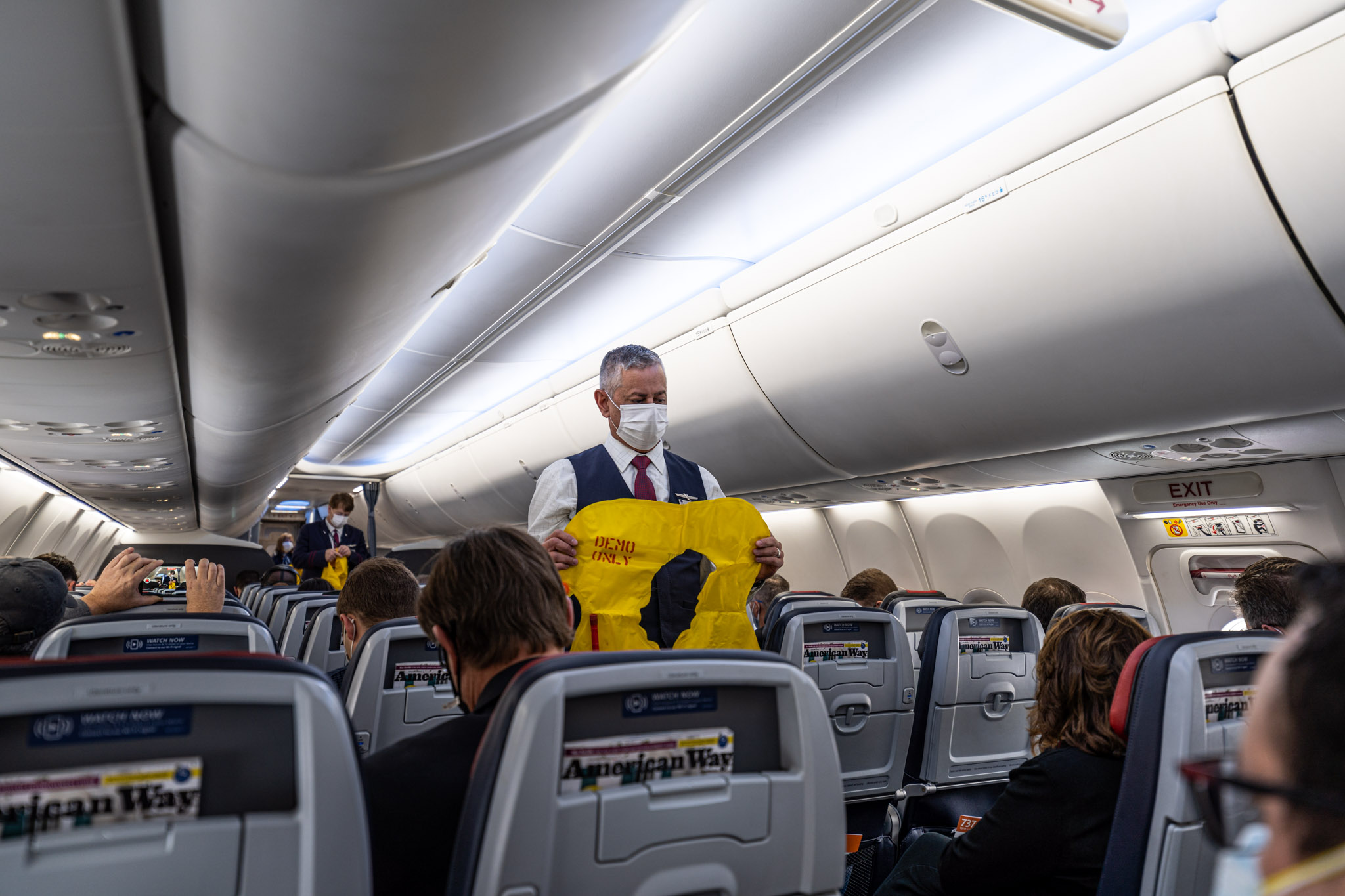 a man wearing a mask and holding a yellow sign on an airplane