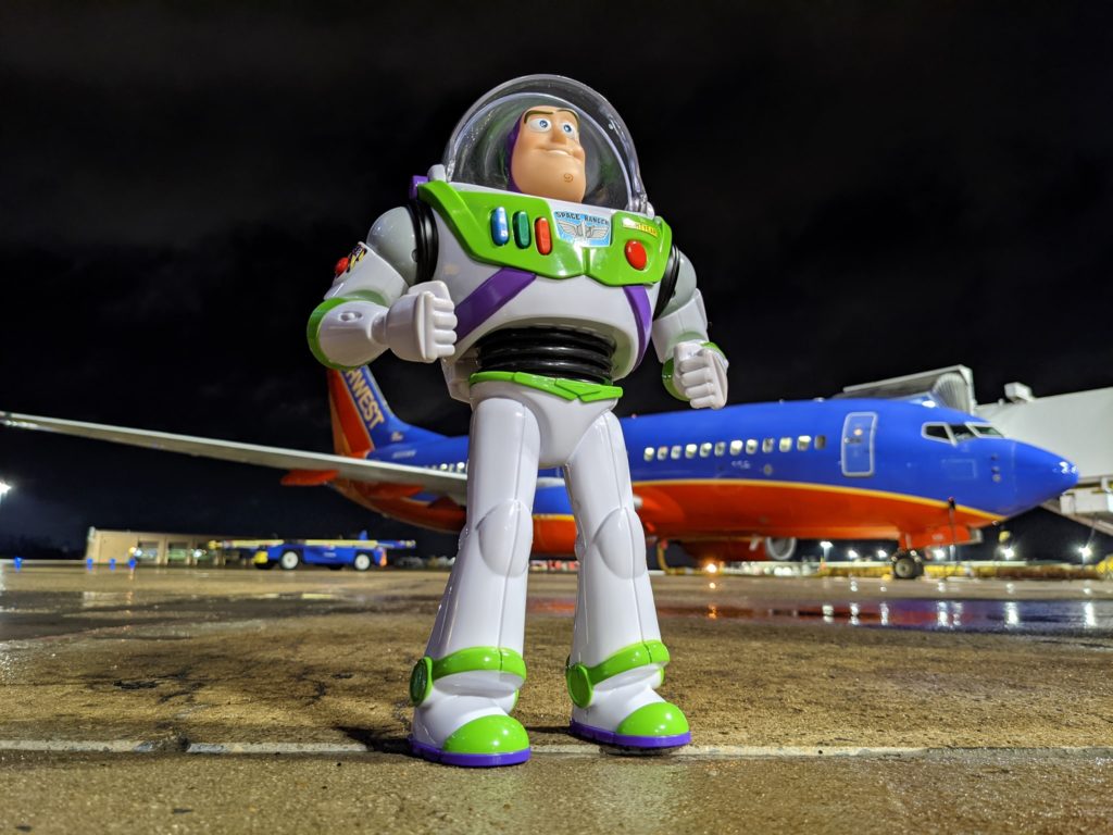 a toy astronaut standing in front of an airplane