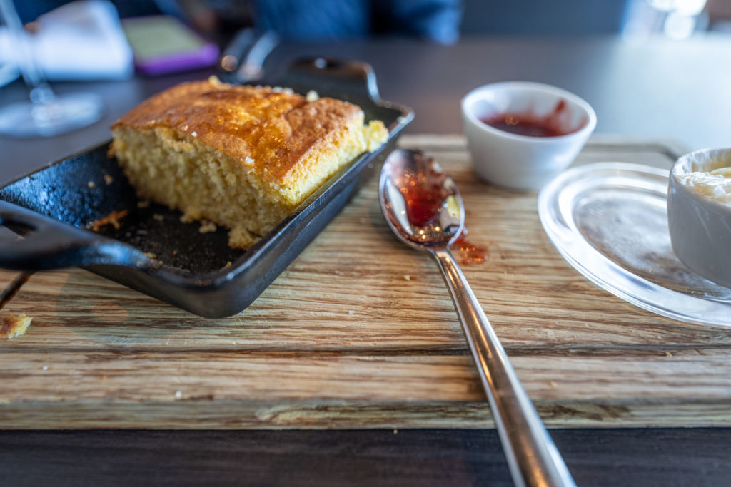 a piece of cornbread in a pan next to a spoon and sauce