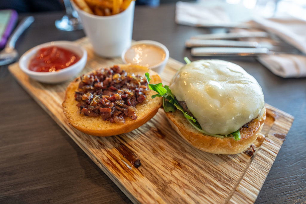 a burger with bacon and cheese on a wooden board