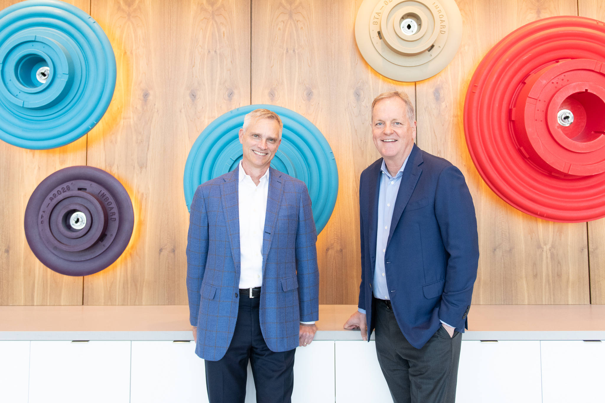 two men standing in front of a wall with colorful circles