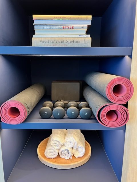 a shelf with yoga mats and books
