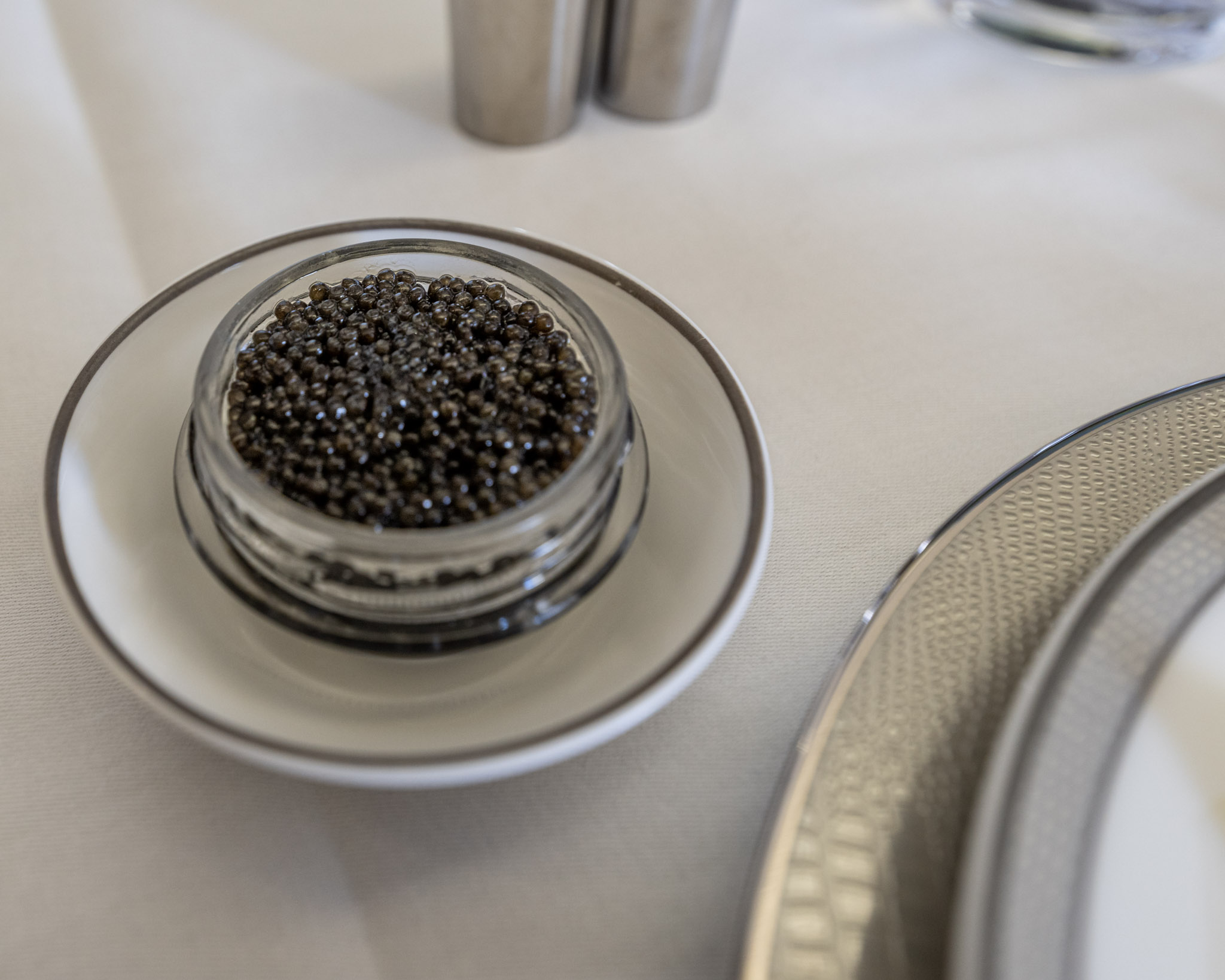 a small glass container with black caviar on a white plate