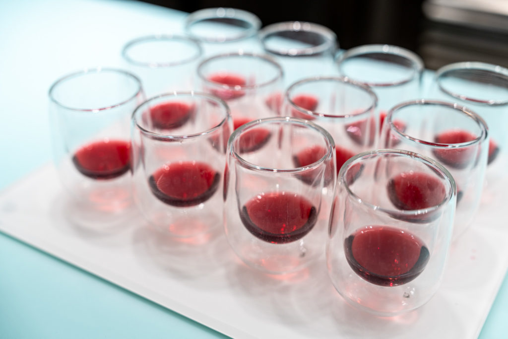 a group of glasses with red liquid in them