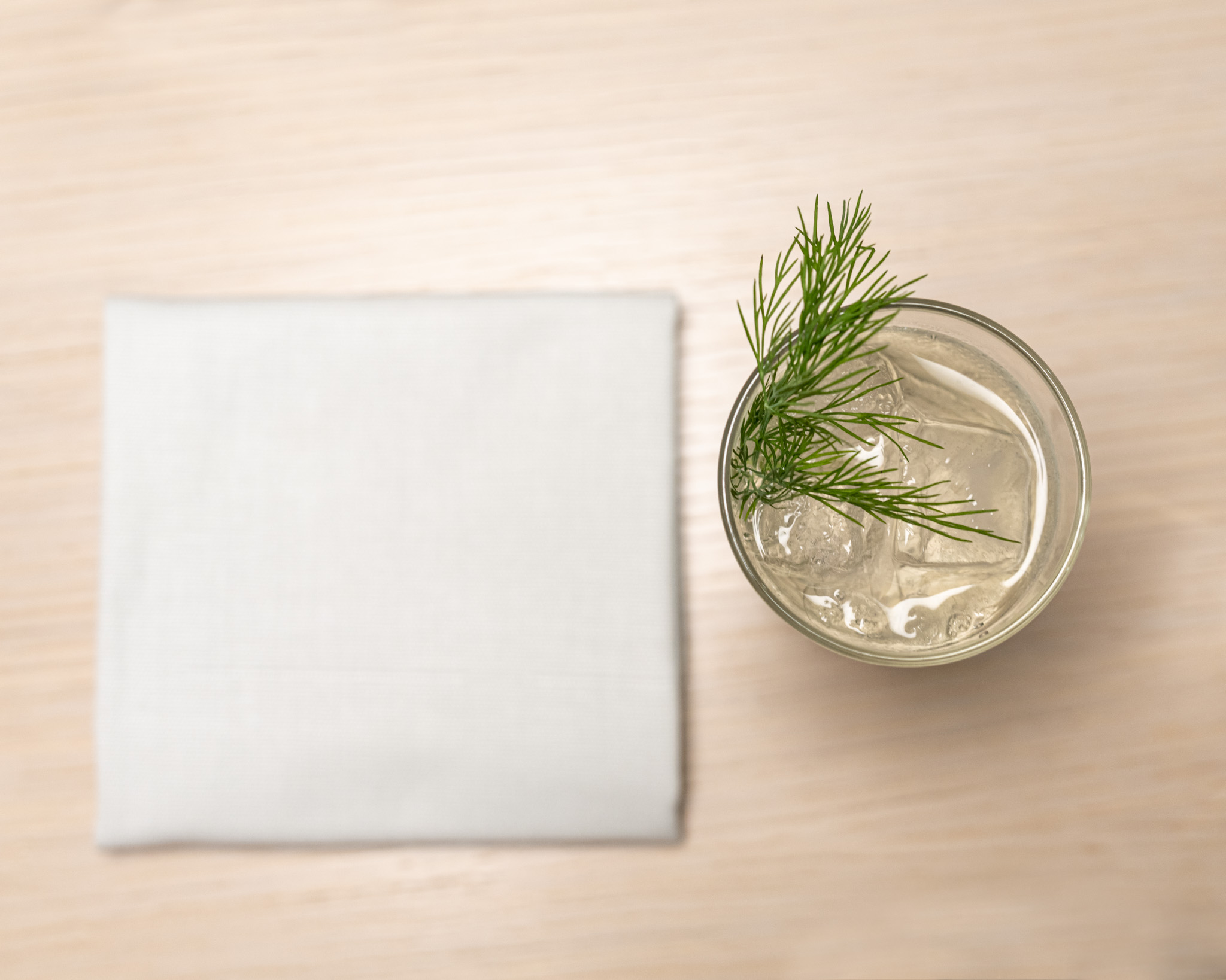 a glass of liquid with ice and a sprig of dill on top