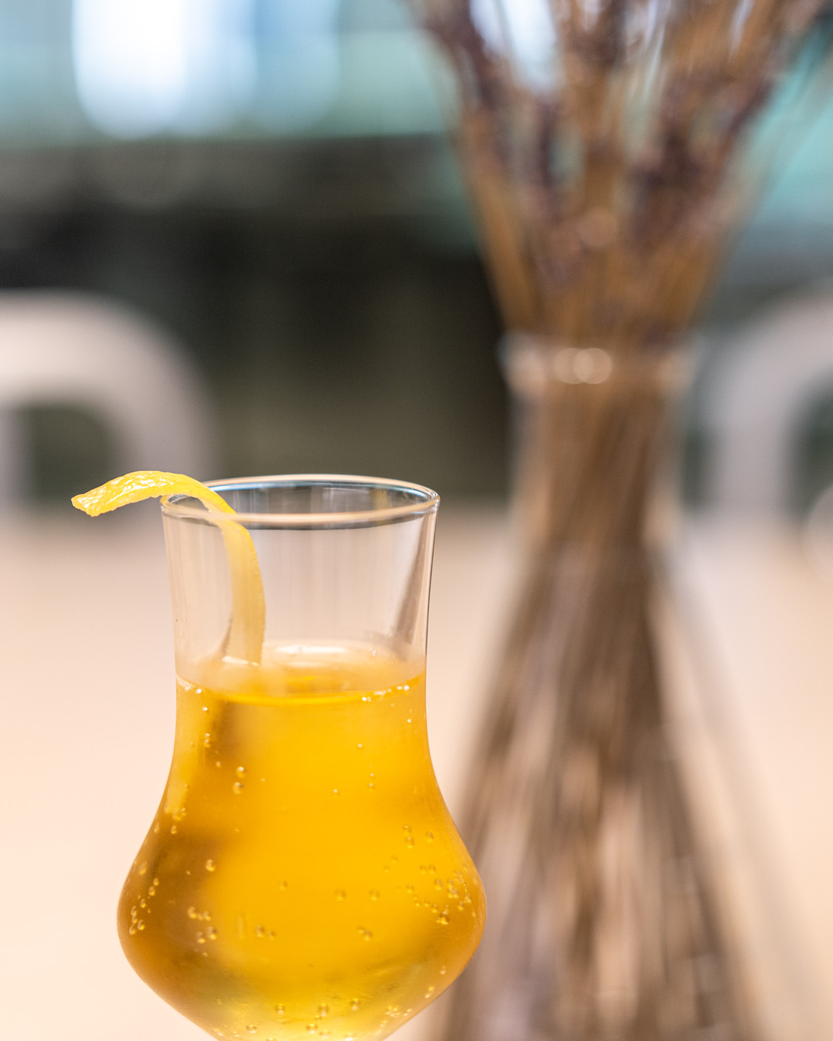 a glass of yellow liquid with a lemon peel in the middle