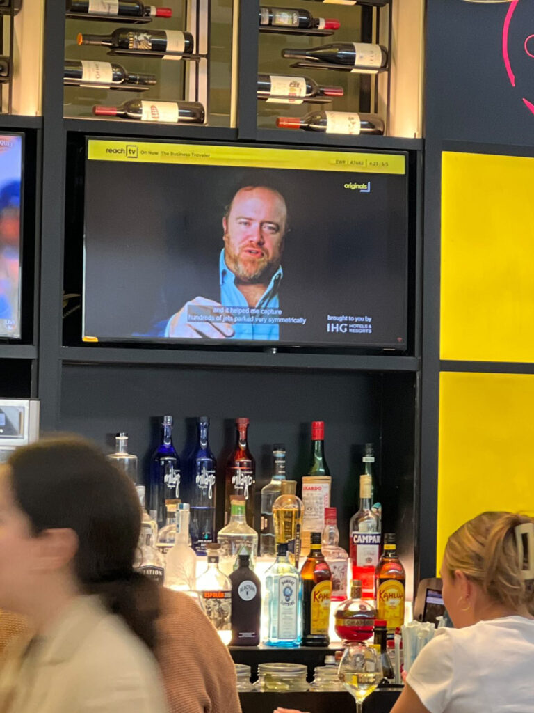 a tv on a shelf with bottles of alcohol