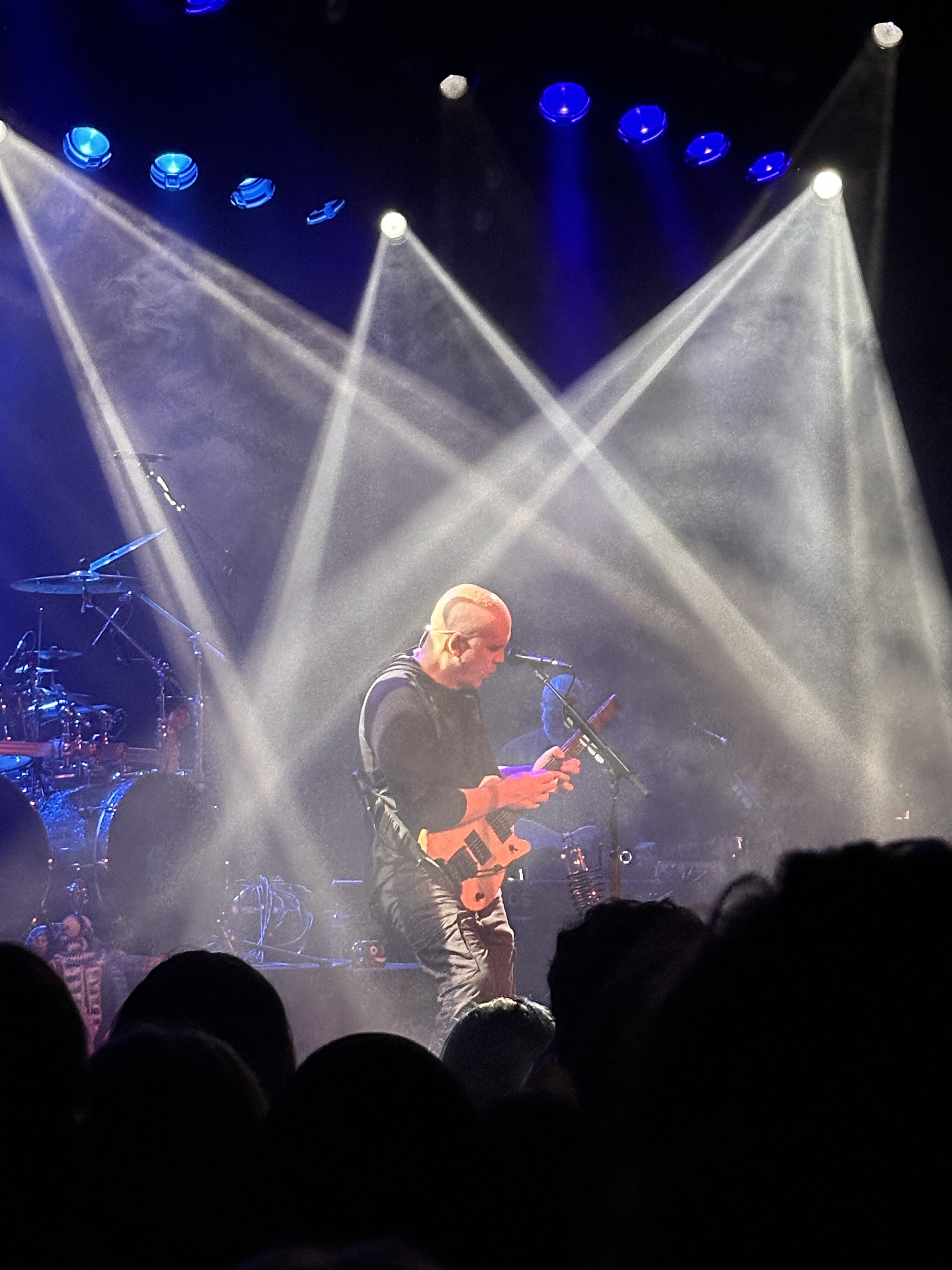 a man playing guitar on stage with spotlights