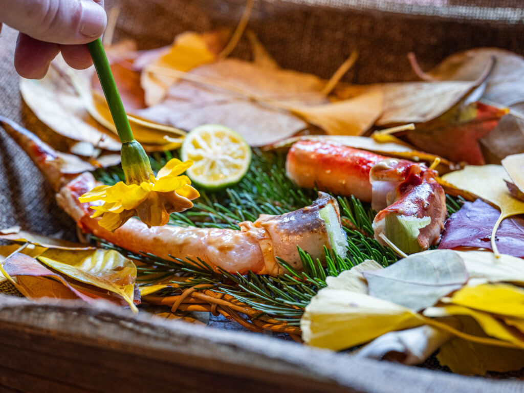 a hand holding a flower over a plate of food