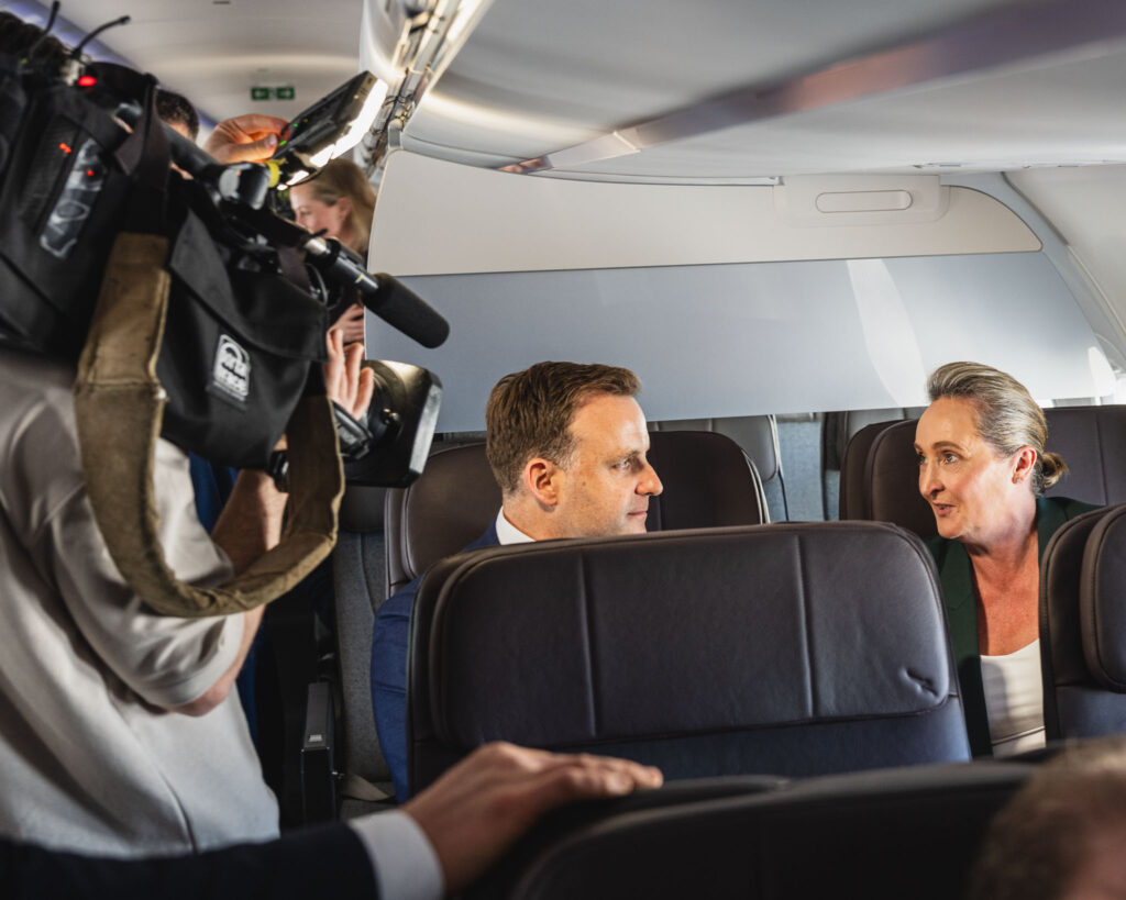 a man taking a picture of a woman sitting in a plane