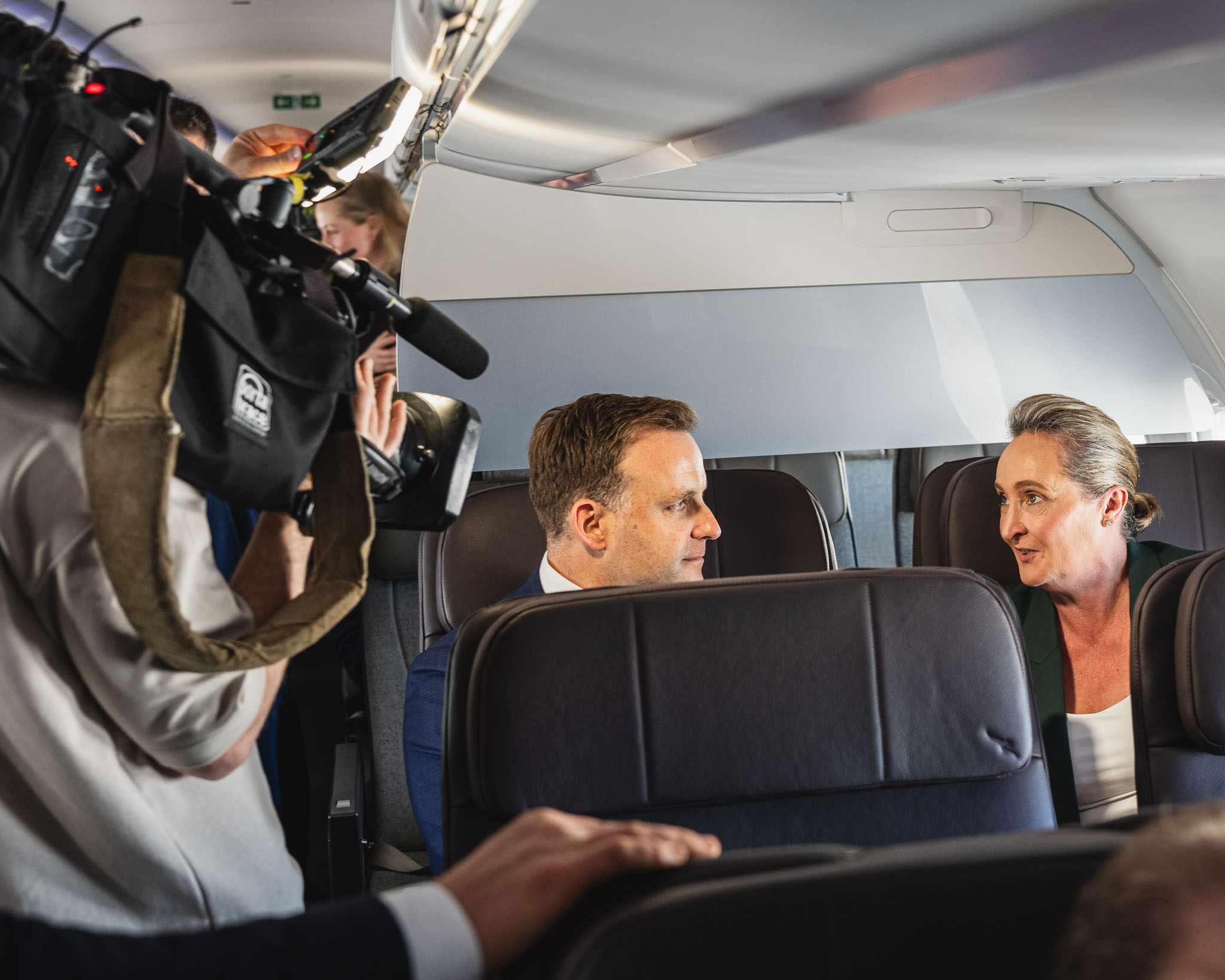 a man taking a picture of a woman sitting in a plane