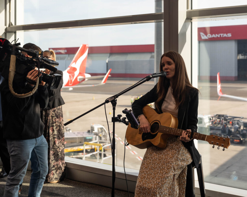 a woman singing into a microphone with a man taking pictures of her