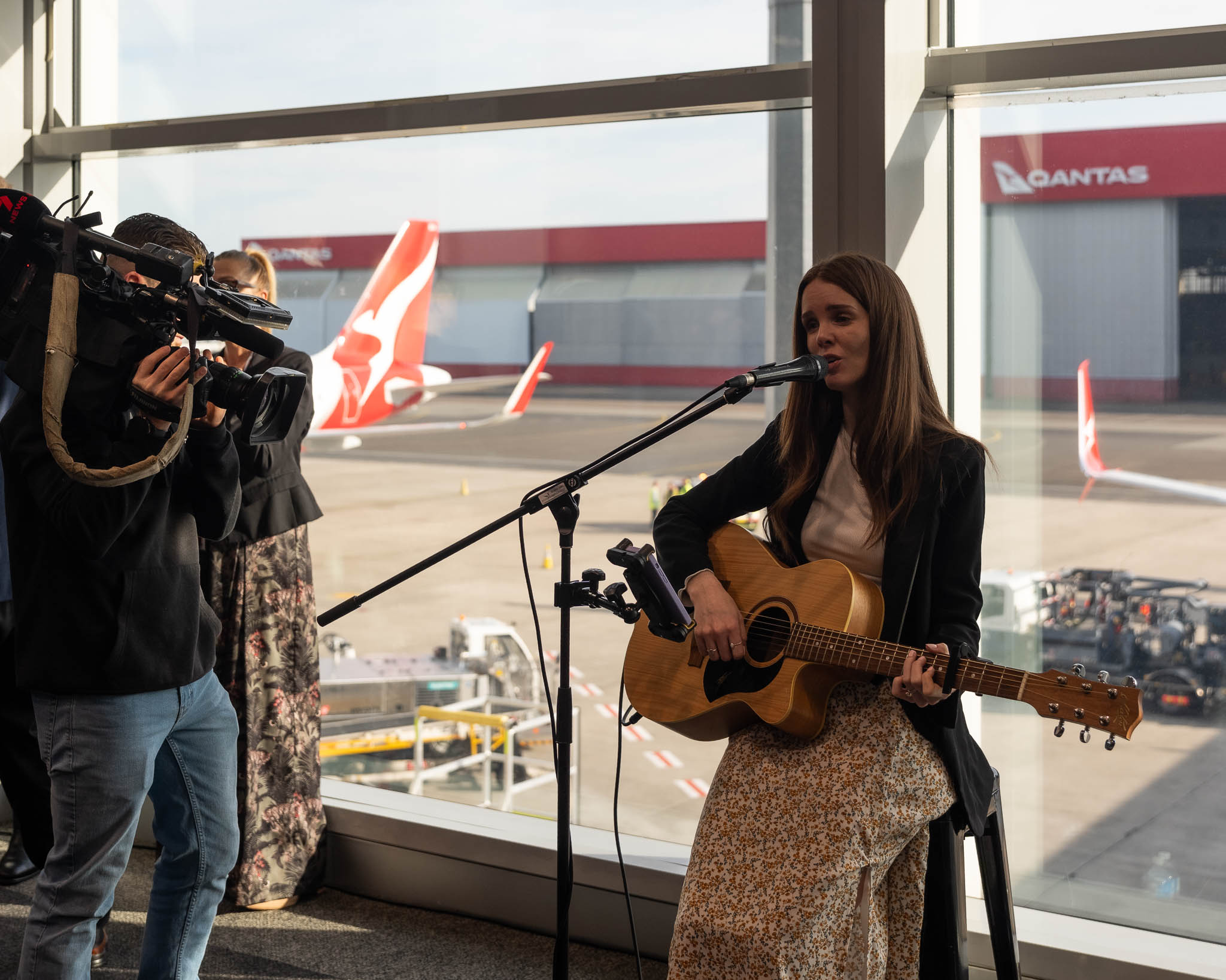 a woman singing into a microphone with a man taking pictures of her