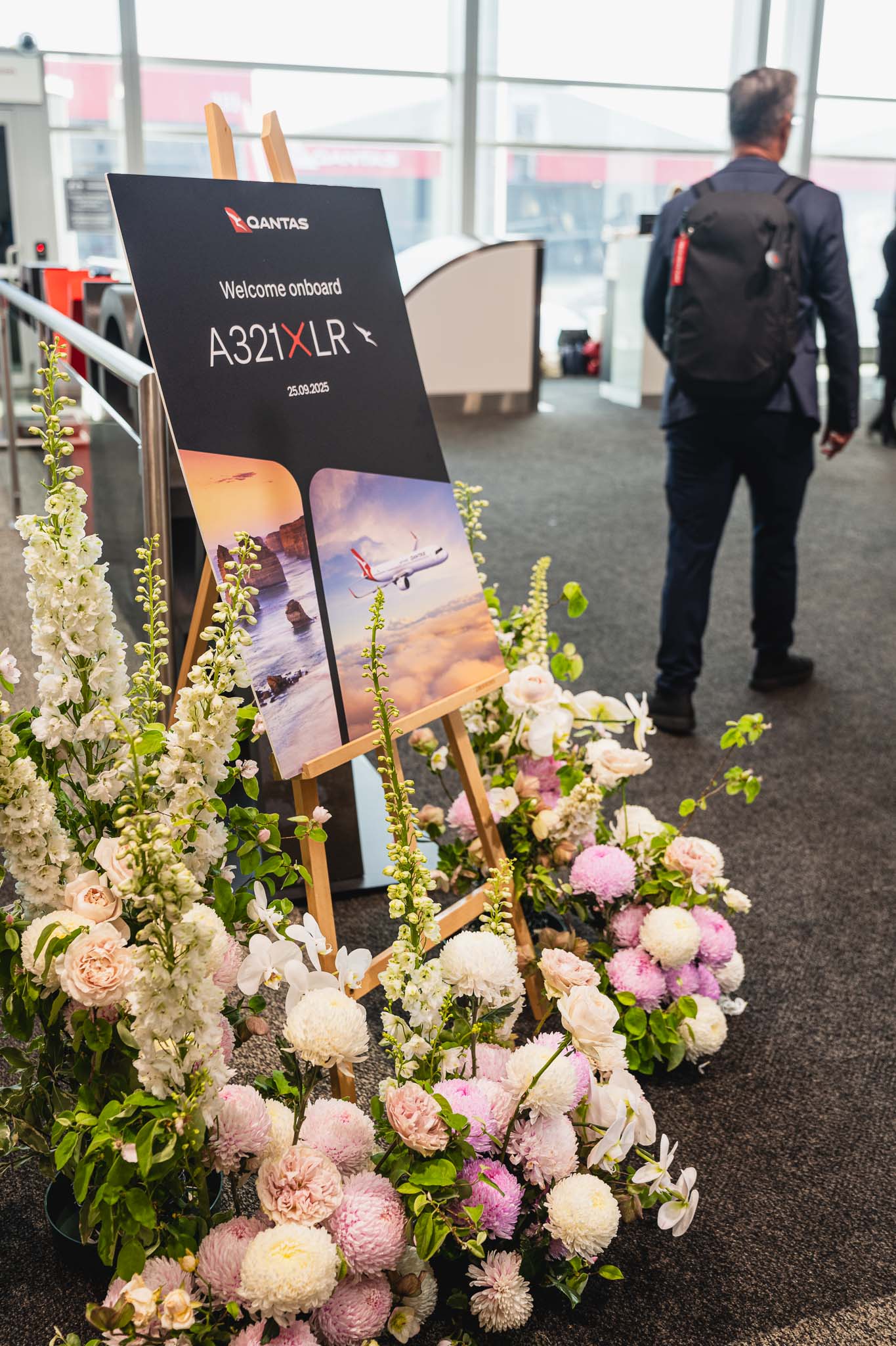 a sign with flowers and a man walking in the background